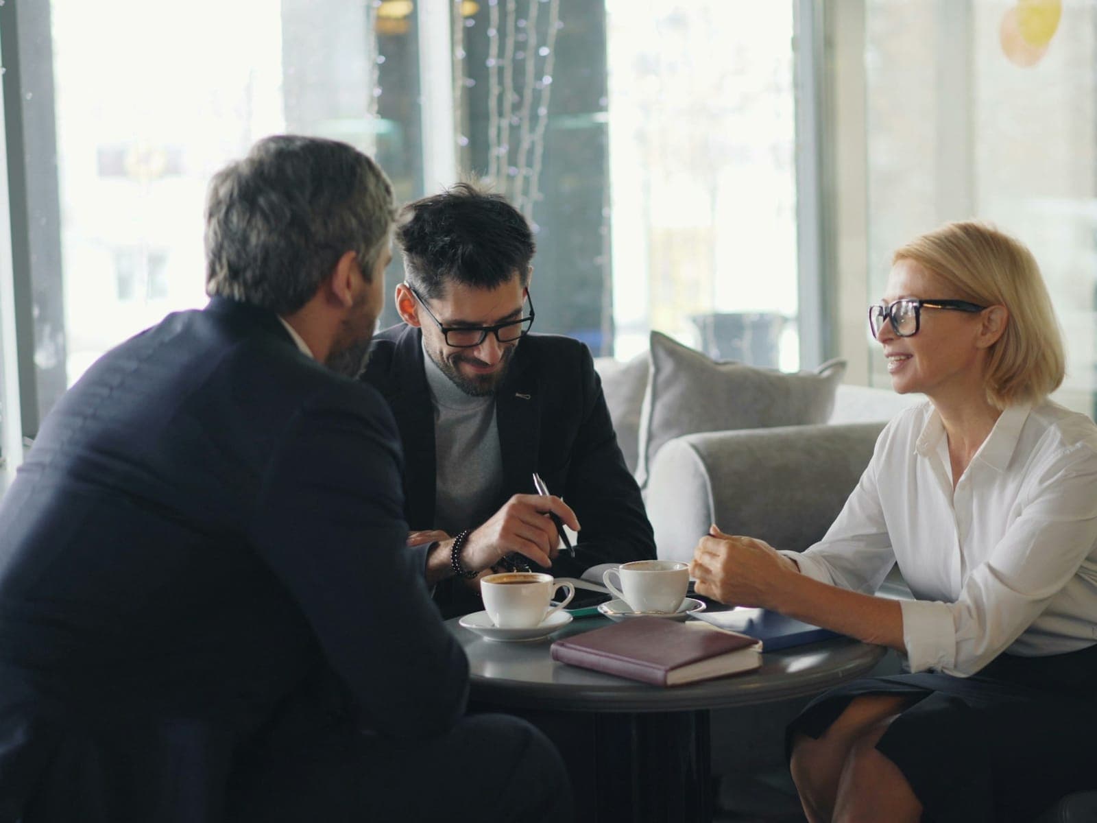 Three colleagues in conversation across a conference table