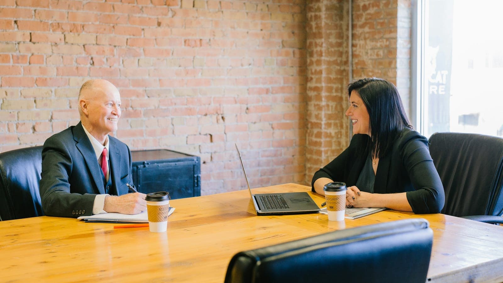 Two people talking across a desk in a private office