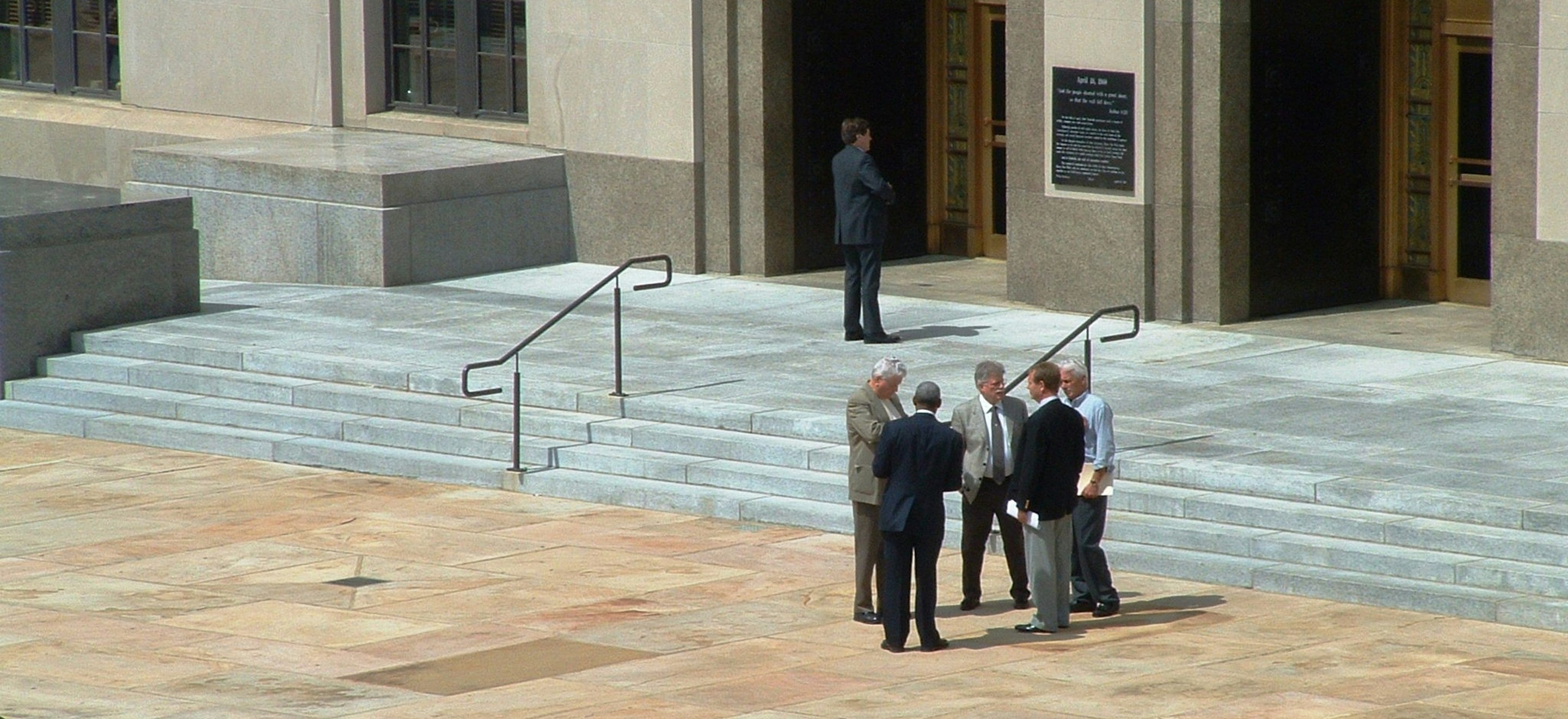 Professionals in suits conferring on the steps of a stone building