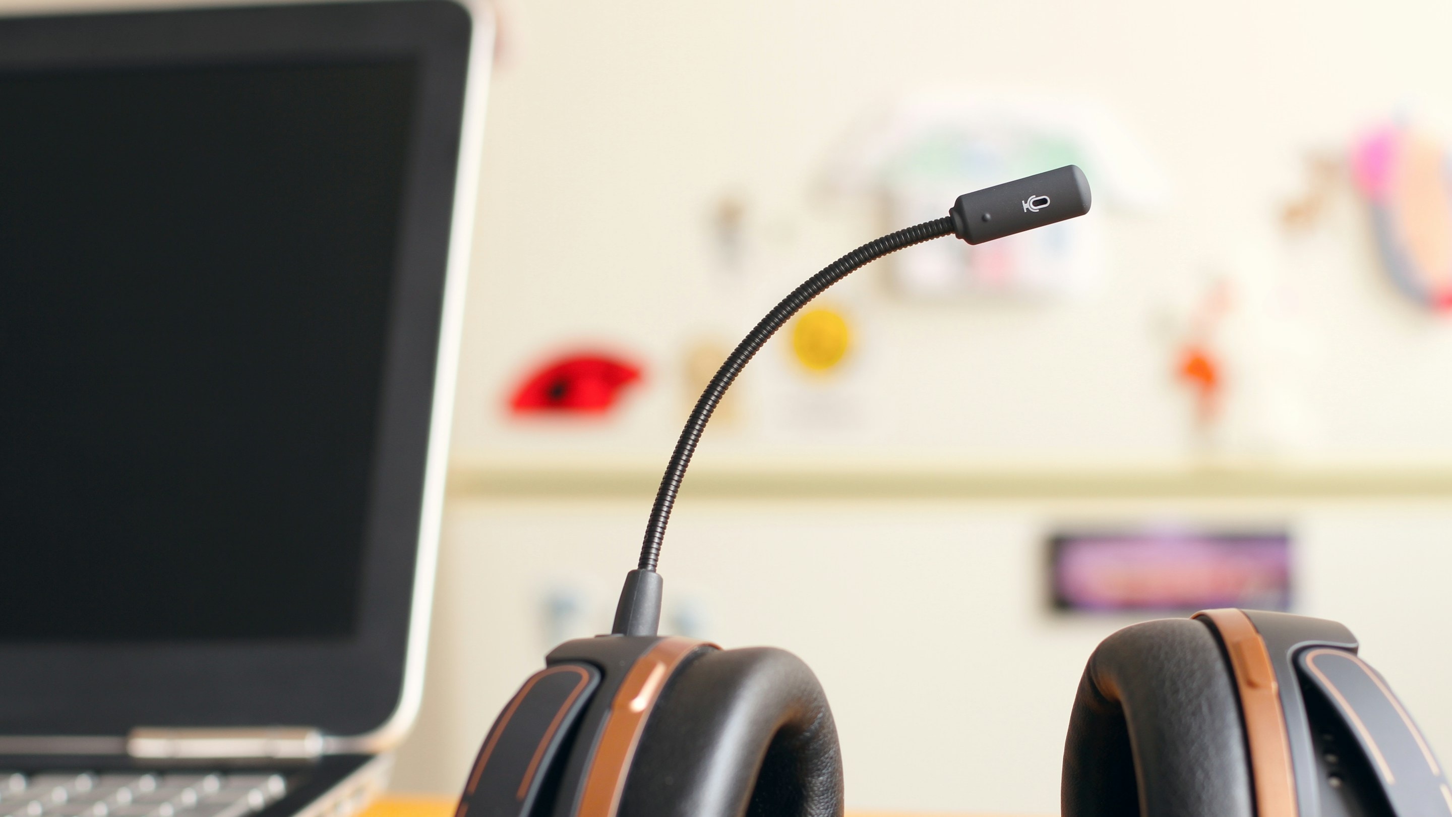 A headset with a boom microphone on a desk beside a laptop