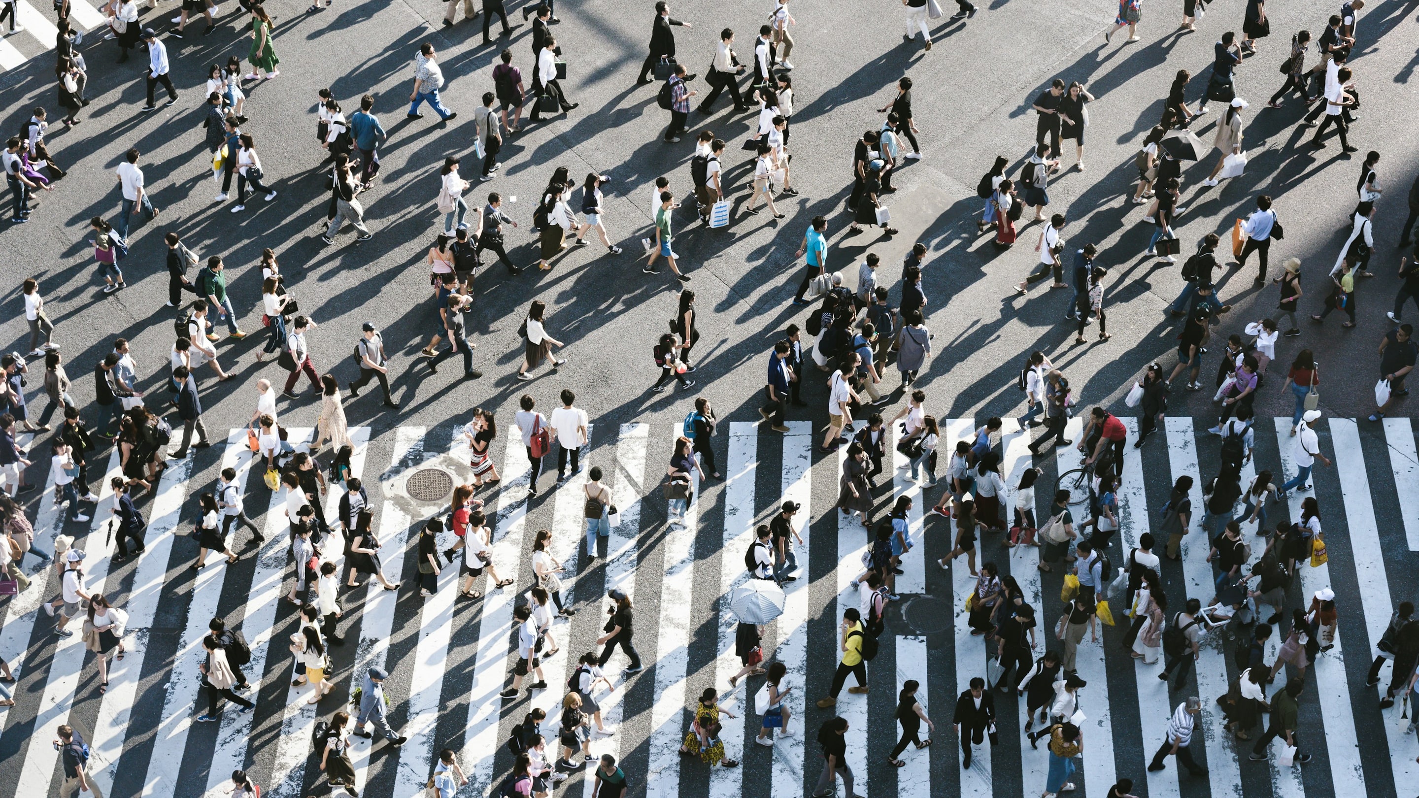 A crowd of people crossing a wide crosswalk, seen from above
