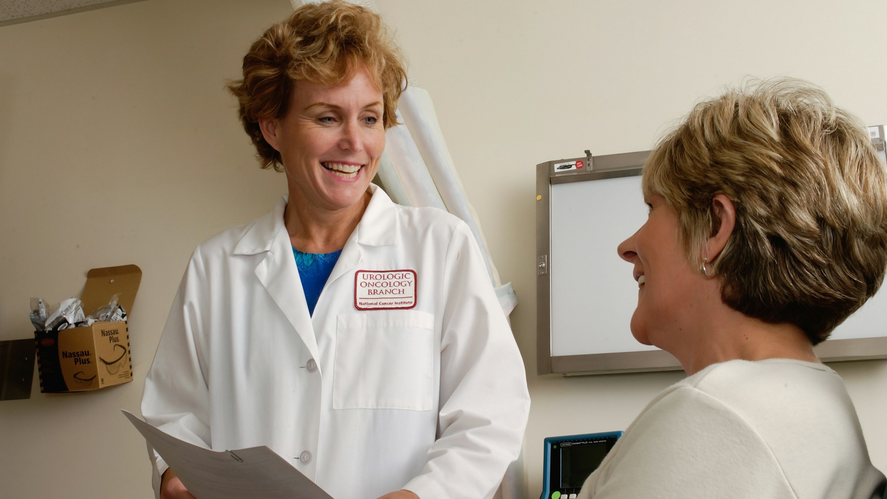 A smiling doctor in a white coat talking with a patient in a clinic