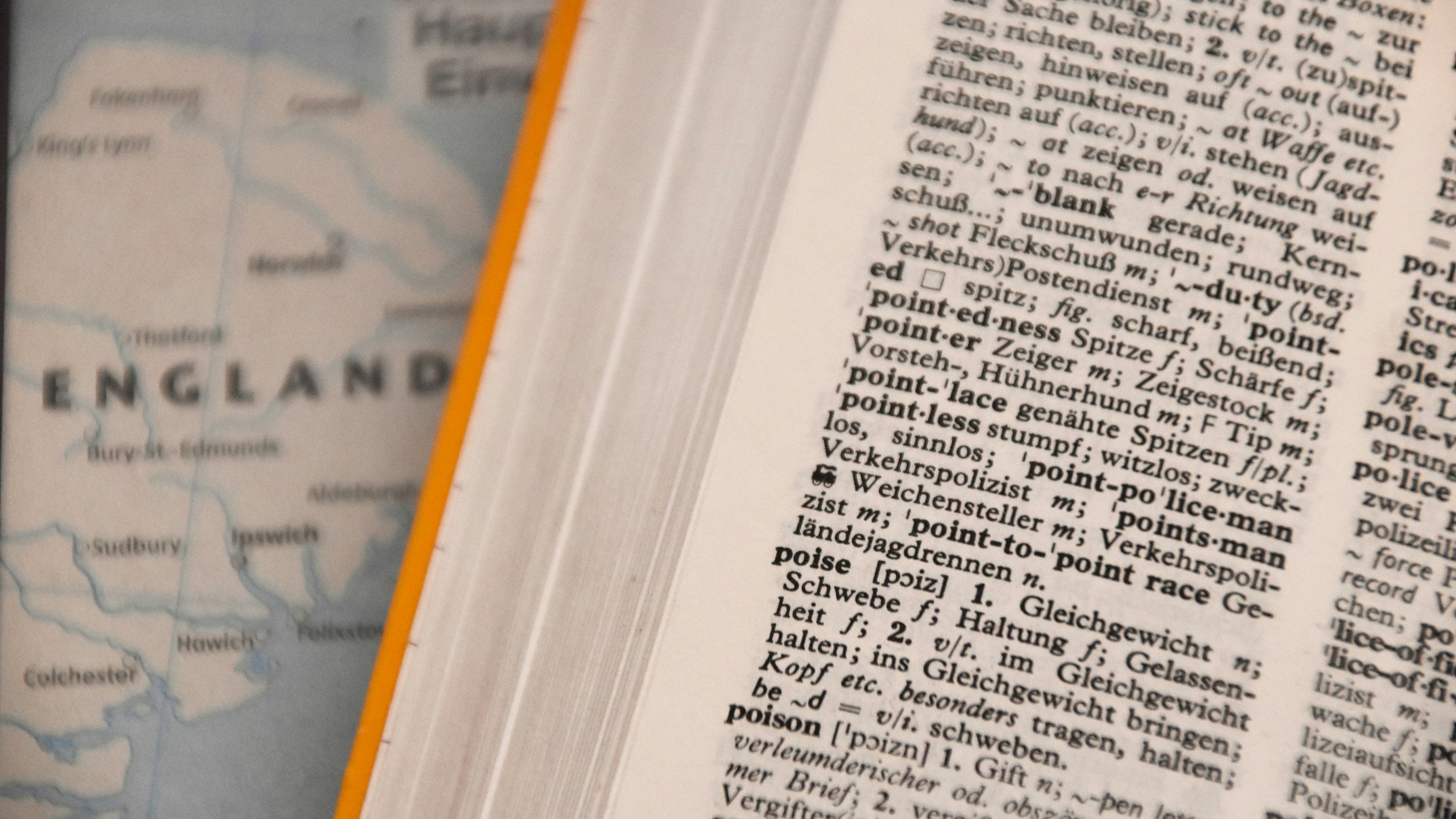An open English and German dictionary lying on a map